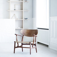 Mid-century modern chair in rich walnut, featuring a smooth wood grain and minimalistic design against a light backdrop.