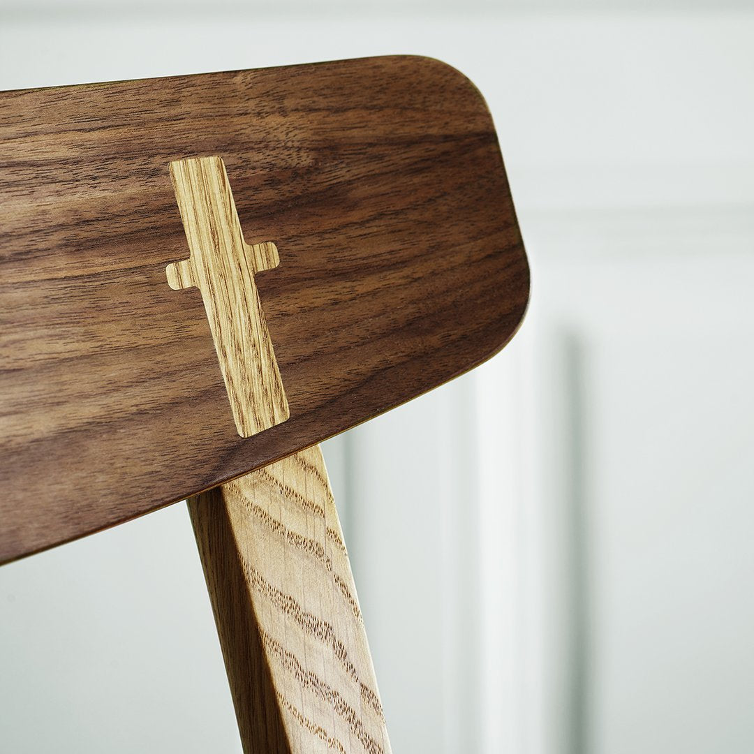 Wooden chair detail showcasing a rich walnut finish with light ash accents and a sleek design.