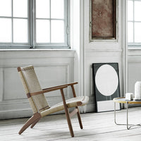 Light beige woven chair with wooden frame, featuring a minimalist design against a neutral backdrop.