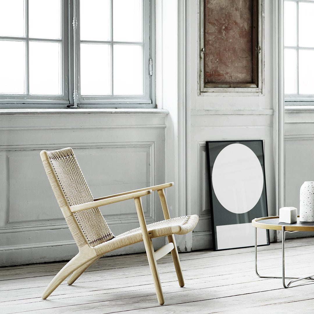 Natural-colored wicker chair in a minimalist setting with light wood accents and neutral tones. Modern, airy design.
