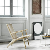 Natural-colored wicker chair in a minimalist setting with light wood accents and neutral tones. Modern, airy design.