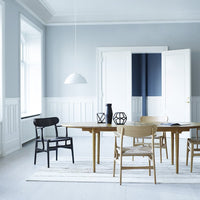 Modern dining room featuring a light blue wall, white furniture, and a mix of black and wooden chair designs.