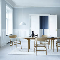 Light blue walls and white trim, paired with a natural wood table and chairs on a striped rug for a fresh, modern look.