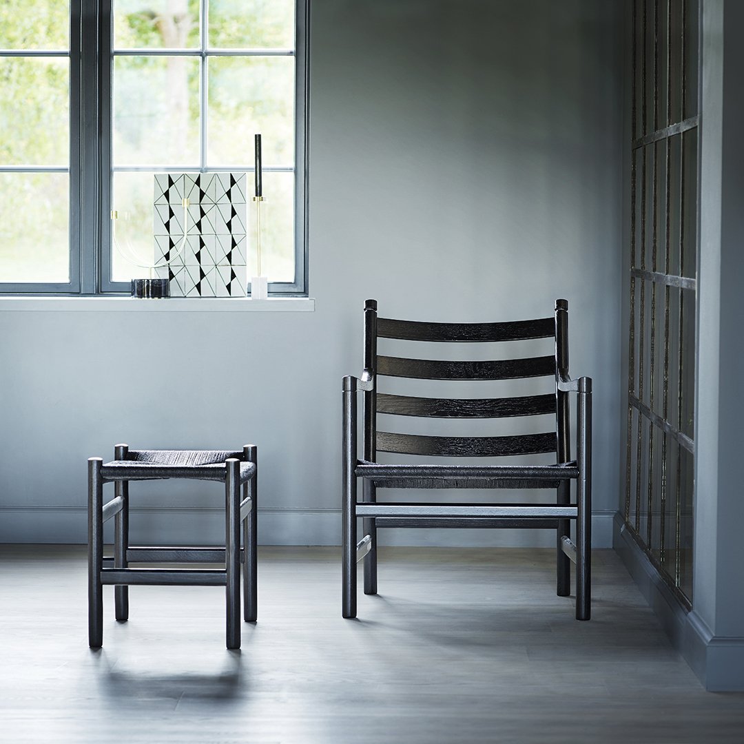 Modern black striped chairs and stool in a minimalist gray room with natural light. Elegant and stylish design.