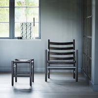 Modern black striped chairs and stool in a minimalist gray room with natural light. Elegant and stylish design.