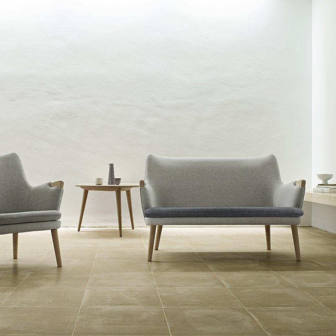 Gray and light blue upholstered sofa set with wooden legs on a neutral-toned tiled floor in a minimalist space.