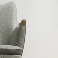 Light gray upholstered armchair with smooth, subtle texture and natural wood accents. Modern, minimalist design.