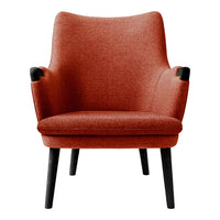 Terra-cotta upholstered armchair with a sleek black base, featuring simple, modern lines and a cozy texture.