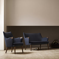 Navy blue upholstered sofa and armchair with wooden accents against a minimalist beige wall and floor.