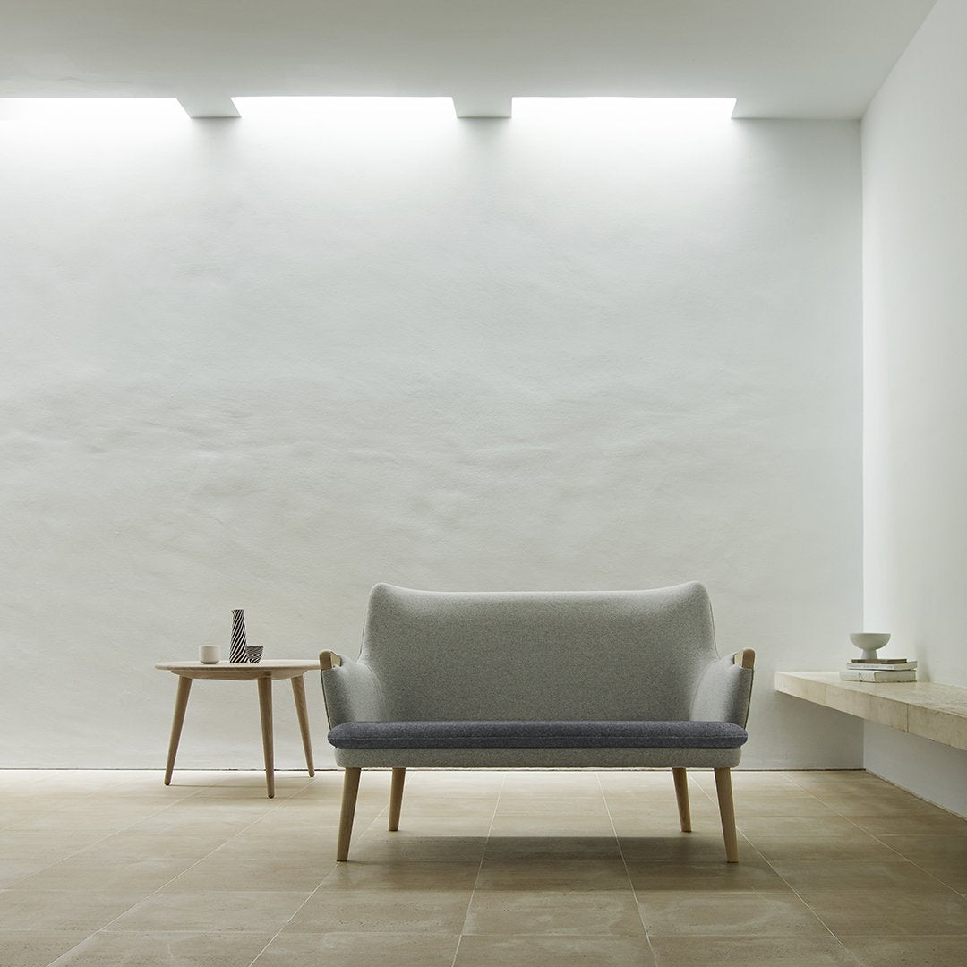 Light gray and soft blue two-tone sofa with minimalist design, set against a neutral wall and warm tile flooring.