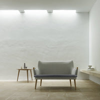 Light gray and soft blue two-tone sofa with minimalist design, set against a neutral wall and warm tile flooring.