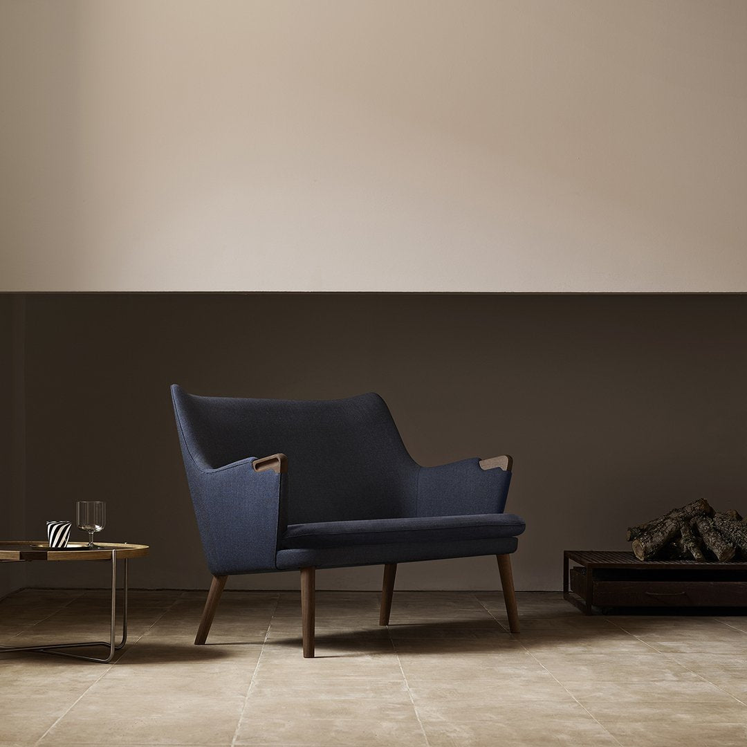 Navy blue upholstered sofa with wooden accents, complemented by a neutral wall and warm beige floor tiles.