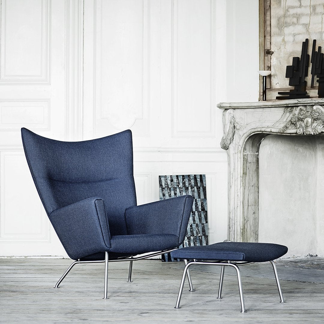 Navy blue upholstered chair with modern silhouette and simple chrome legs, paired with a matching ottoman.
