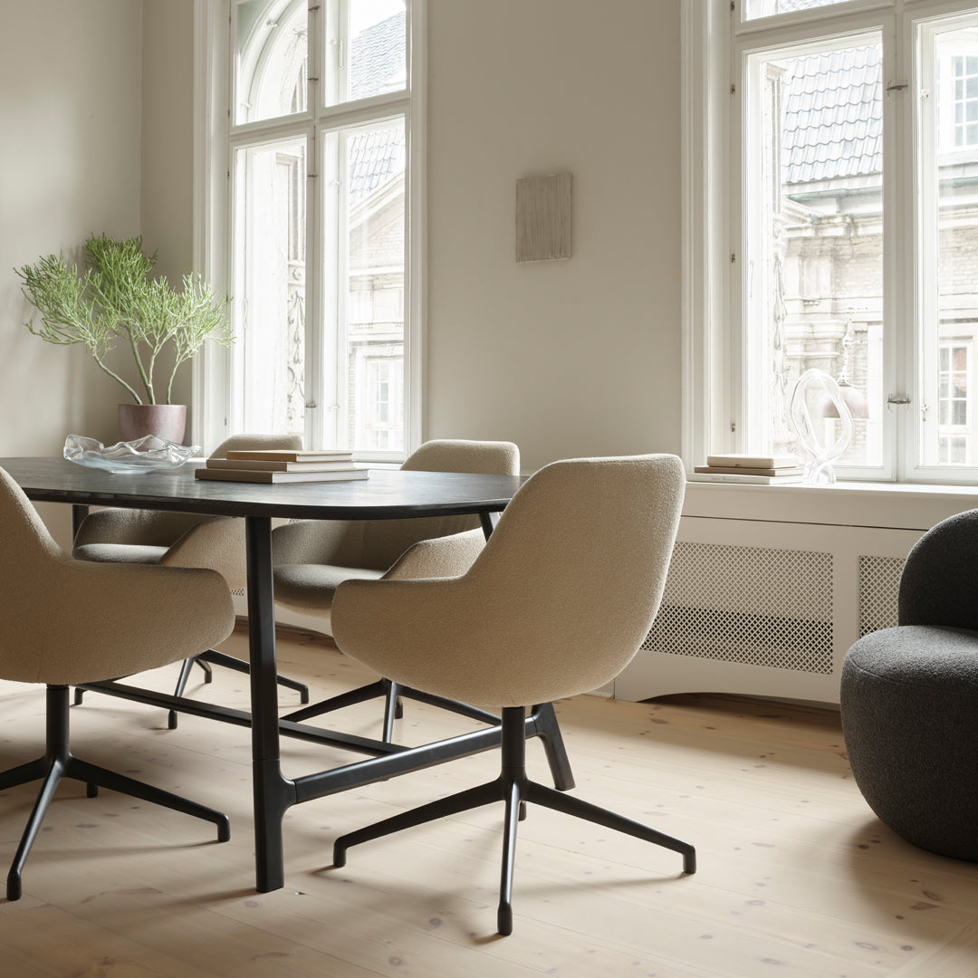 Neutral beige dining chairs with a sleek black metal base, paired with a round black dining table in a modern setting.
