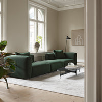 Green textured sofa with minimalistic design, accented by neutral walls and soft gray rug in a bright room.