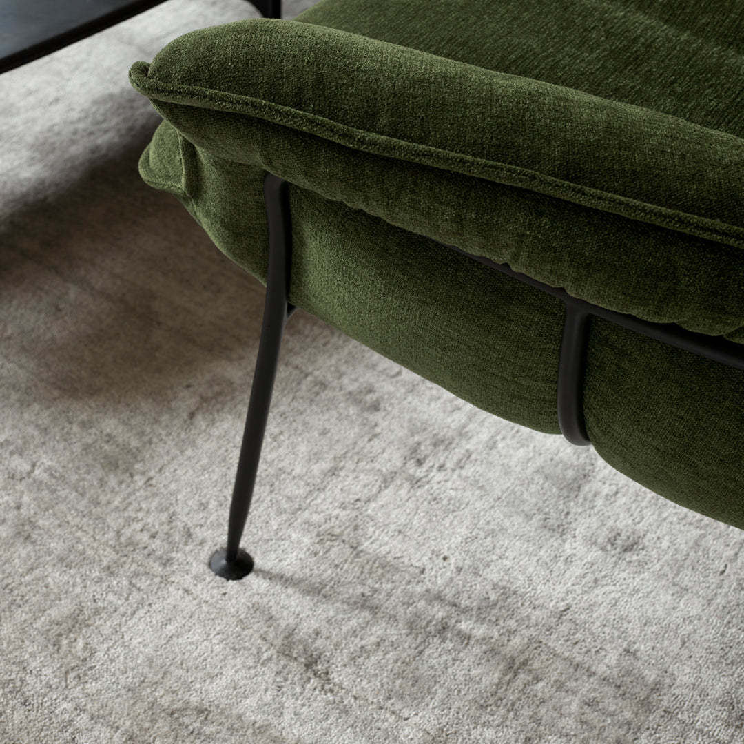 Green upholstered chair with subtle texture, featuring sleek black metal legs, set against a light gray background.