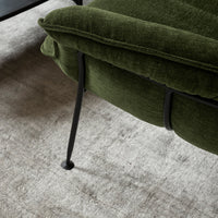 Green upholstered chair with subtle texture, featuring sleek black metal legs, set against a light gray background.