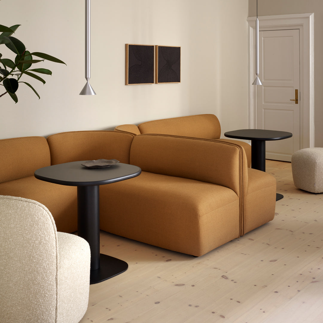 Tan and cream upholstery with modern shapes and minimalist black tables against a light wood floor backdrop.