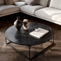 Black marble coffee table with subtle white veins and sleek metal frame, complemented by a minimalist decor setup.
