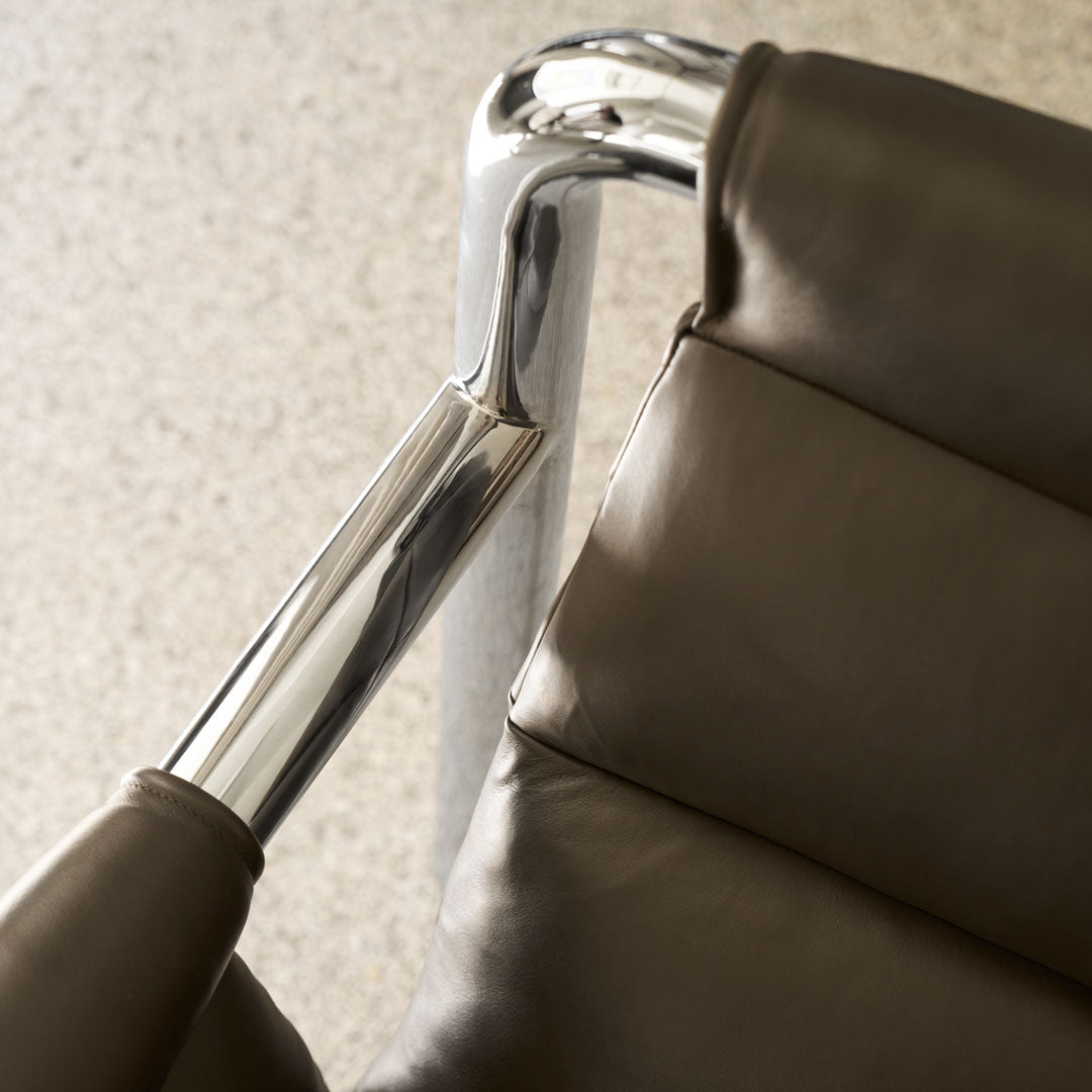 Modern brown leather chair with polished chrome accents, featuring smooth textures and sleek lines.