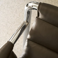 Modern brown leather chair with polished chrome accents, featuring smooth textures and sleek lines.