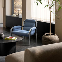 Blue upholstered chair with chrome accents, set against a neutral-toned modern interior. Soft textures and muted colors.