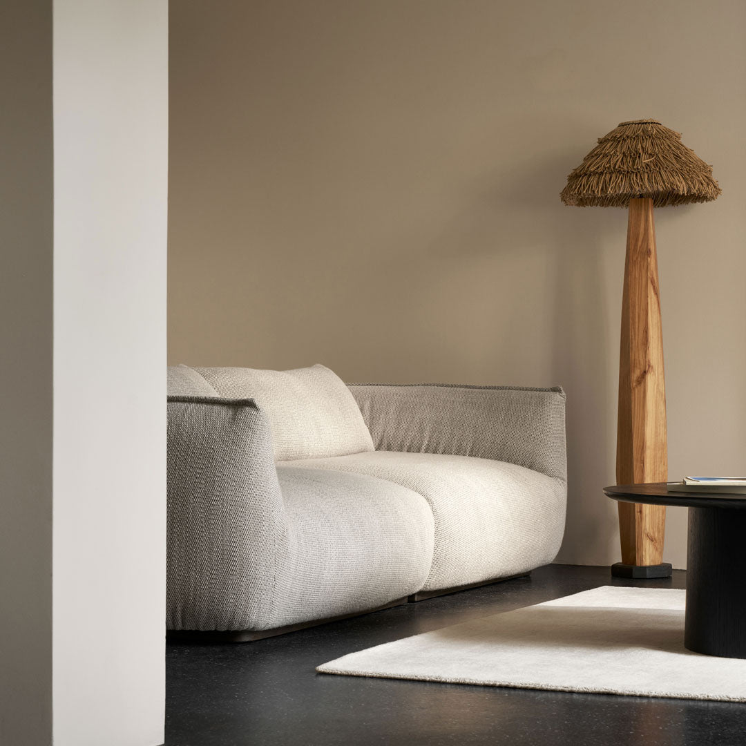 Light beige and gray textured sofa against a warm tan wall, complemented by natural wood and dark accents.