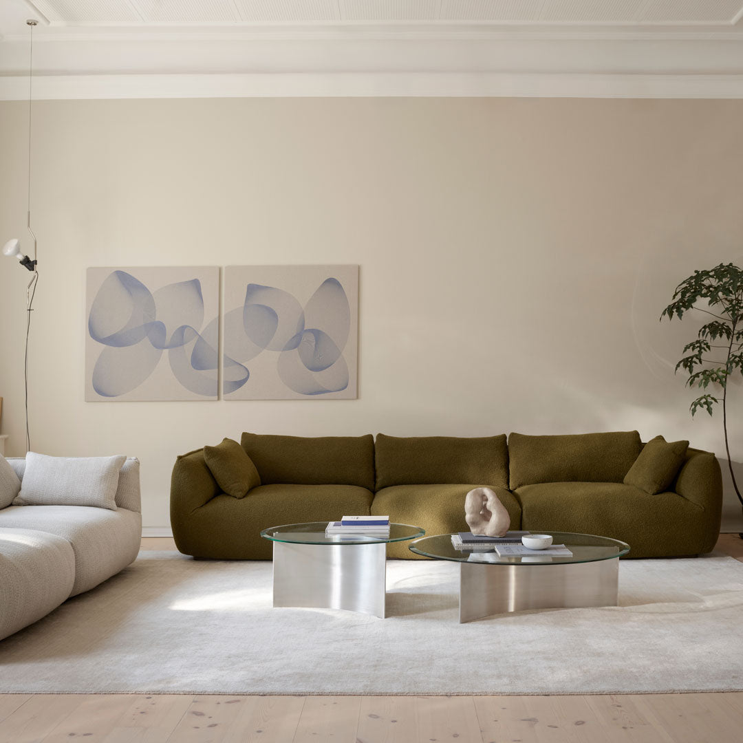 Olive green sofa with rounded edges, soft beige upholstery, and light blue abstract wall art in a neutral room setting.
