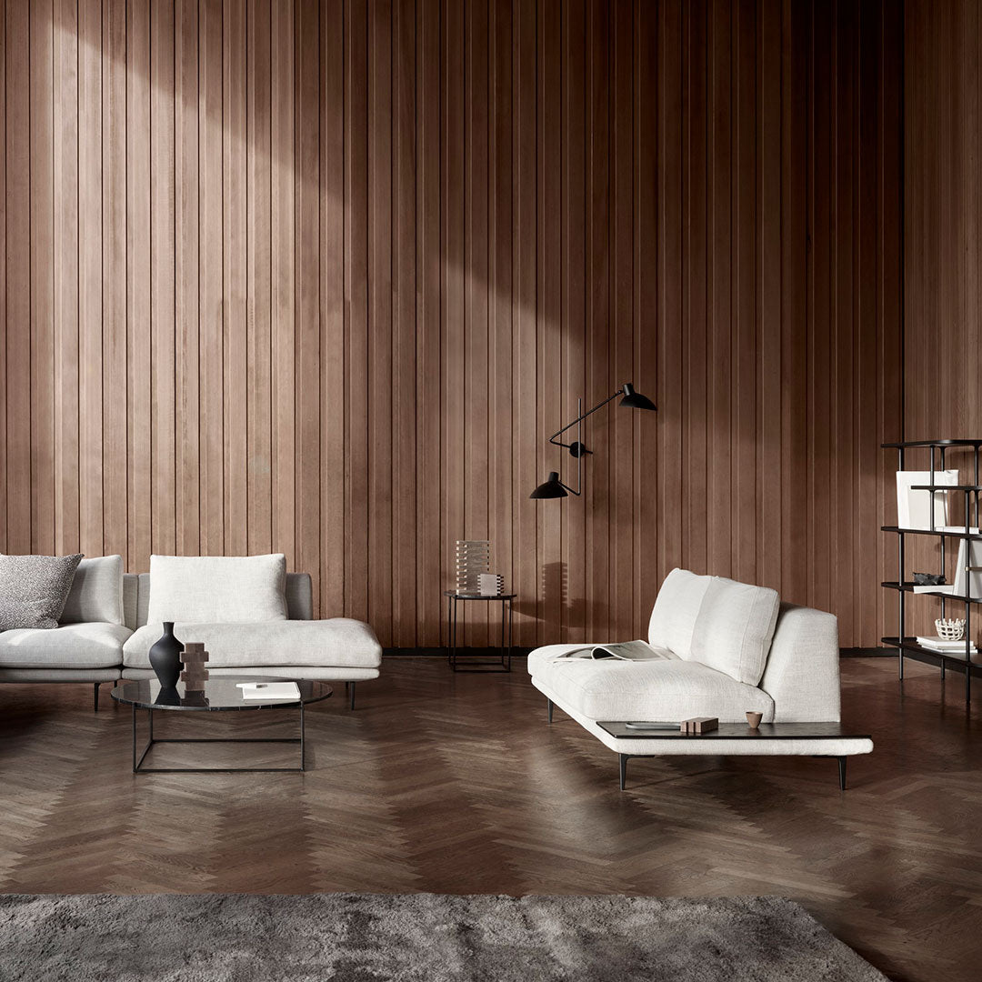 Elegant white sofas against a warm wooden wall, complemented by a dark rug and contemporary black accents.