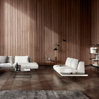 Elegant white sofas against a warm wooden wall, complemented by a dark rug and contemporary black accents.
