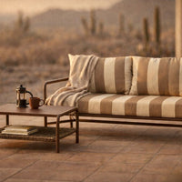 Striped beige and cream cushions on a modern sofa, complemented by a rustic wooden coffee table and soft neutral blanket.