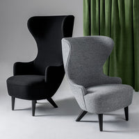 Black and gray upholstered chairs with sleek lines, set against a backdrop of vibrant green curtains.