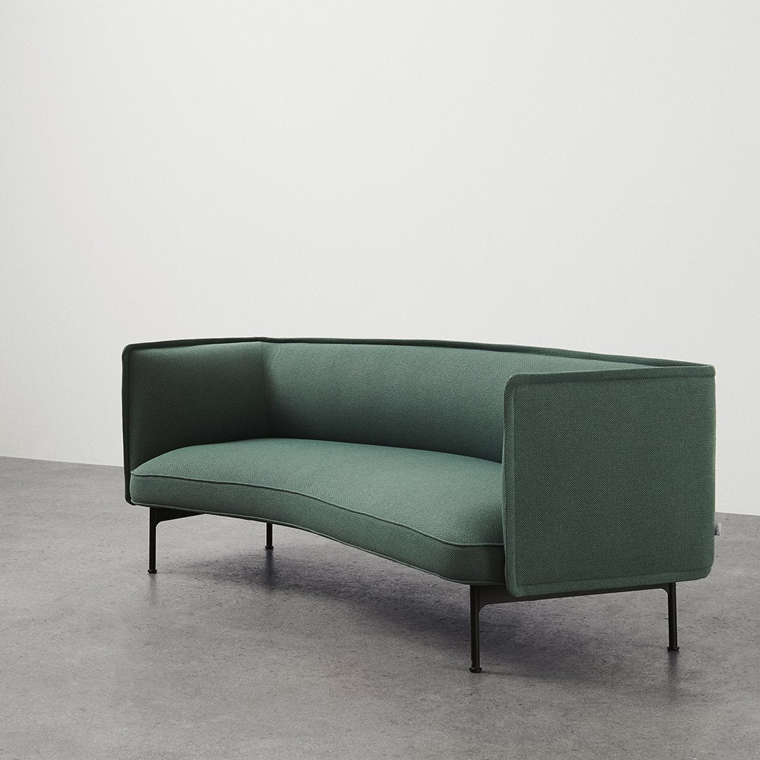 Elegant green upholstered sofa with a sleek curved design and minimalist black legs on a gray floor.