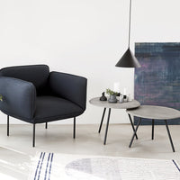 Contemporary navy blue armchair with light grey concrete tables and abstract blue wall art, minimalist design elements.
