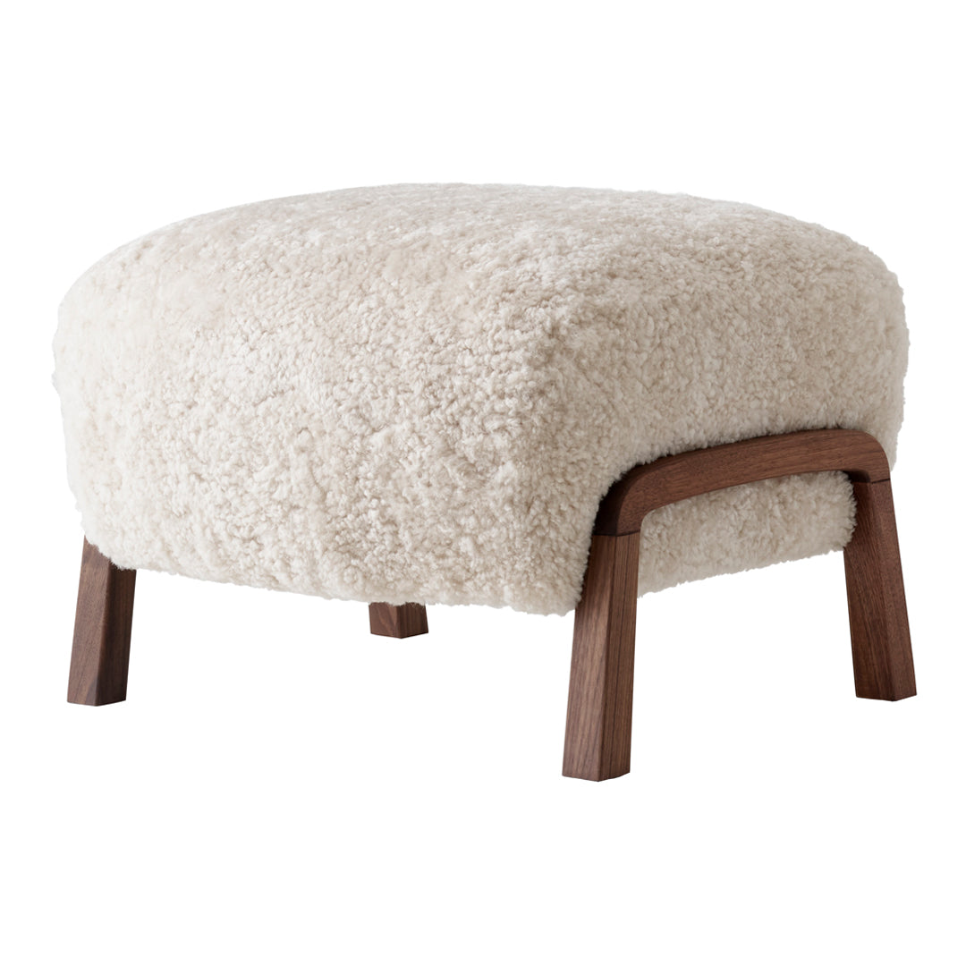 Cozy cream-colored ottoman with a fluffy texture and wooden legs, perfect for modern decor.