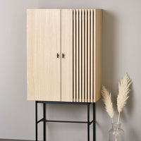 Light oak cabinet with vertical slat design on doors and a sleek black metal base, suited for modern decor.