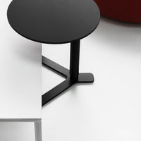 Black round table with a minimalist design, featuring a sleek black base and set against a white surface.