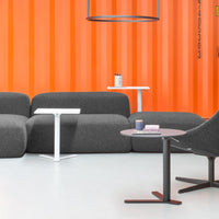 Gray modern sofa with vibrant orange background and white furniture accents, featuring minimalist design elements.