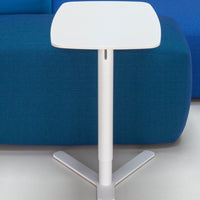 White square side table on a blue upholstered sofa, featuring a sleek, modern design with clean lines.