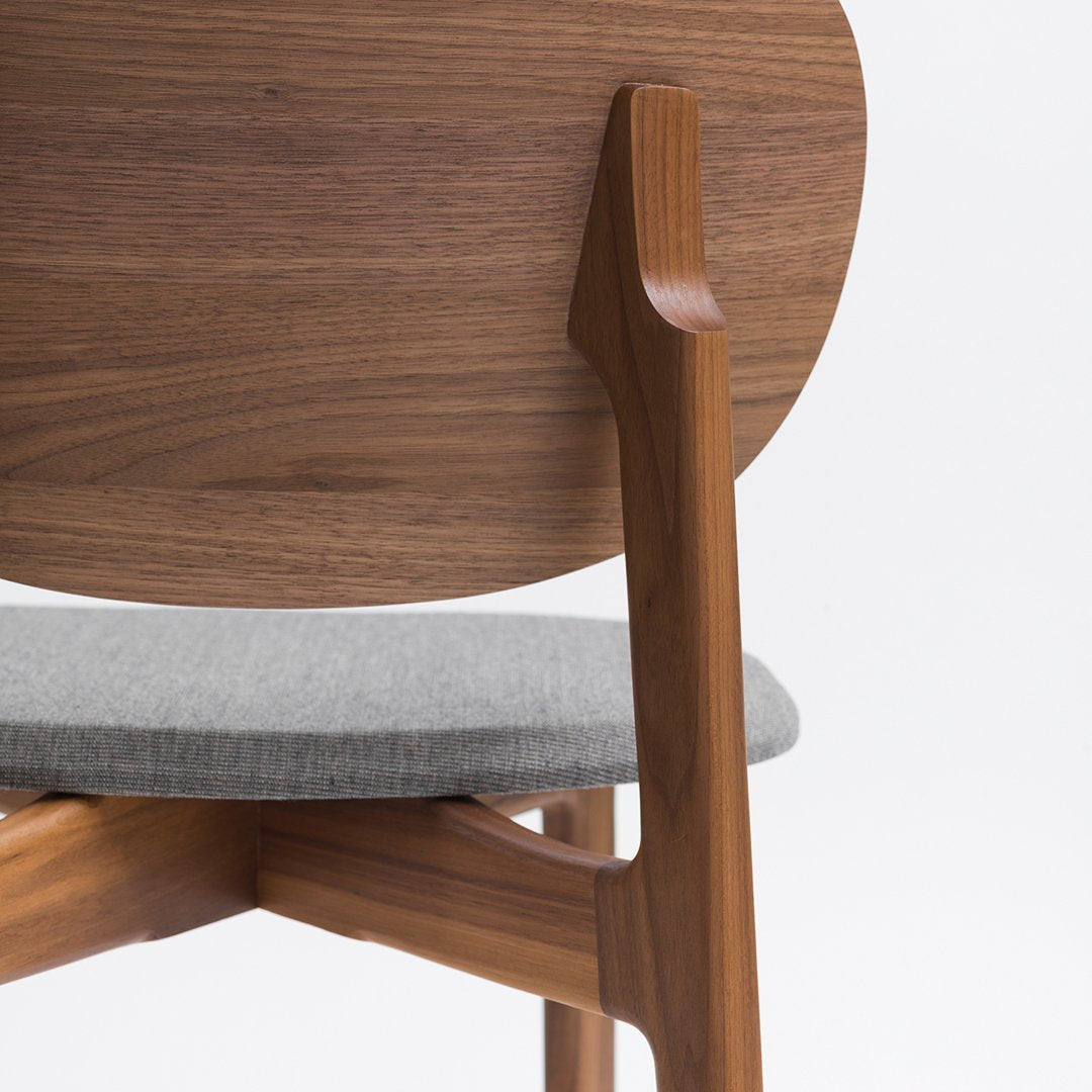 "Wooden chair with a rich walnut finish, grey fabric seat, and smooth round back design."