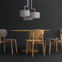 Modern wood dining table with light gray and dark gray upholstered chairs, complemented by gray pendant lamps on a dark backdrop.