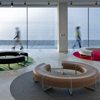 Contemporary lounge seating in black, green, pink, and tan on circular rugs, set in a modern, minimalist space.