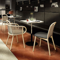 Light beige and gray chairs with woven patterns, complemented by a dark black wall and terracotta flooring.
