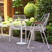 "White striped outdoor chairs and table surrounded by lush green foliage, showcasing modern design and vibrant colors."