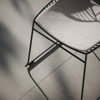 Modern black chair with a light gray fabric seat, featuring sleek lines and minimalist design, set against a neutral floor.