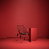Black striped chair against a solid red backdrop with a matching red accent table. Modern, vibrant color scheme.