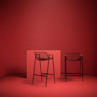Red metal bar stools with sleek lines against a solid red background, creating a bold monochromatic look.