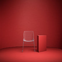 Clear acrylic chair with horizontal lines, set against a solid red backdrop and matching geometric pedestal.
