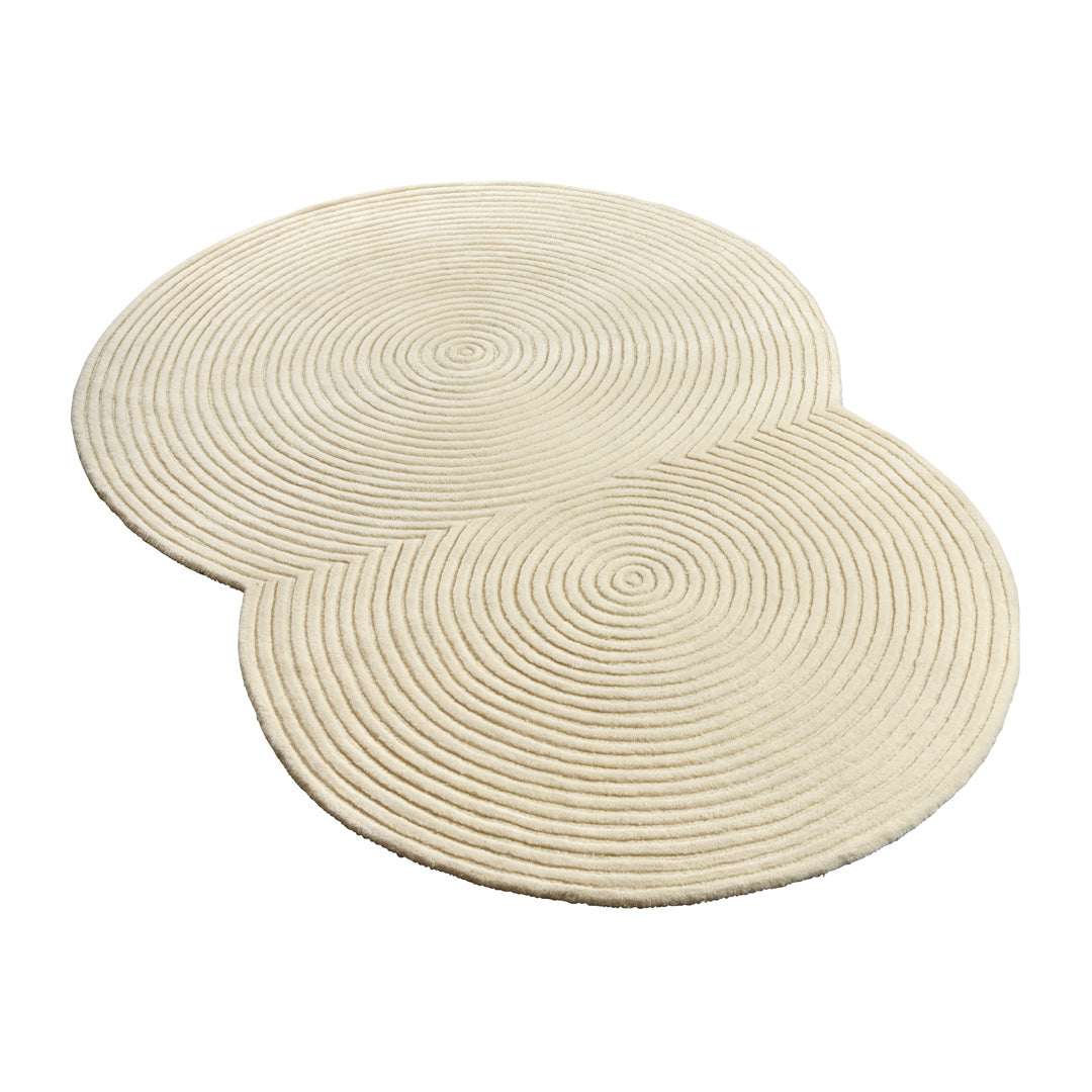 Cream-colored circular rug with textured spiral pattern, adding a modern touch to any space.