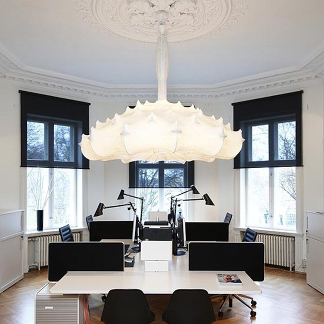 Elegant white chandelier with intricate petal patterns, illuminating a modern workspace with black accents.